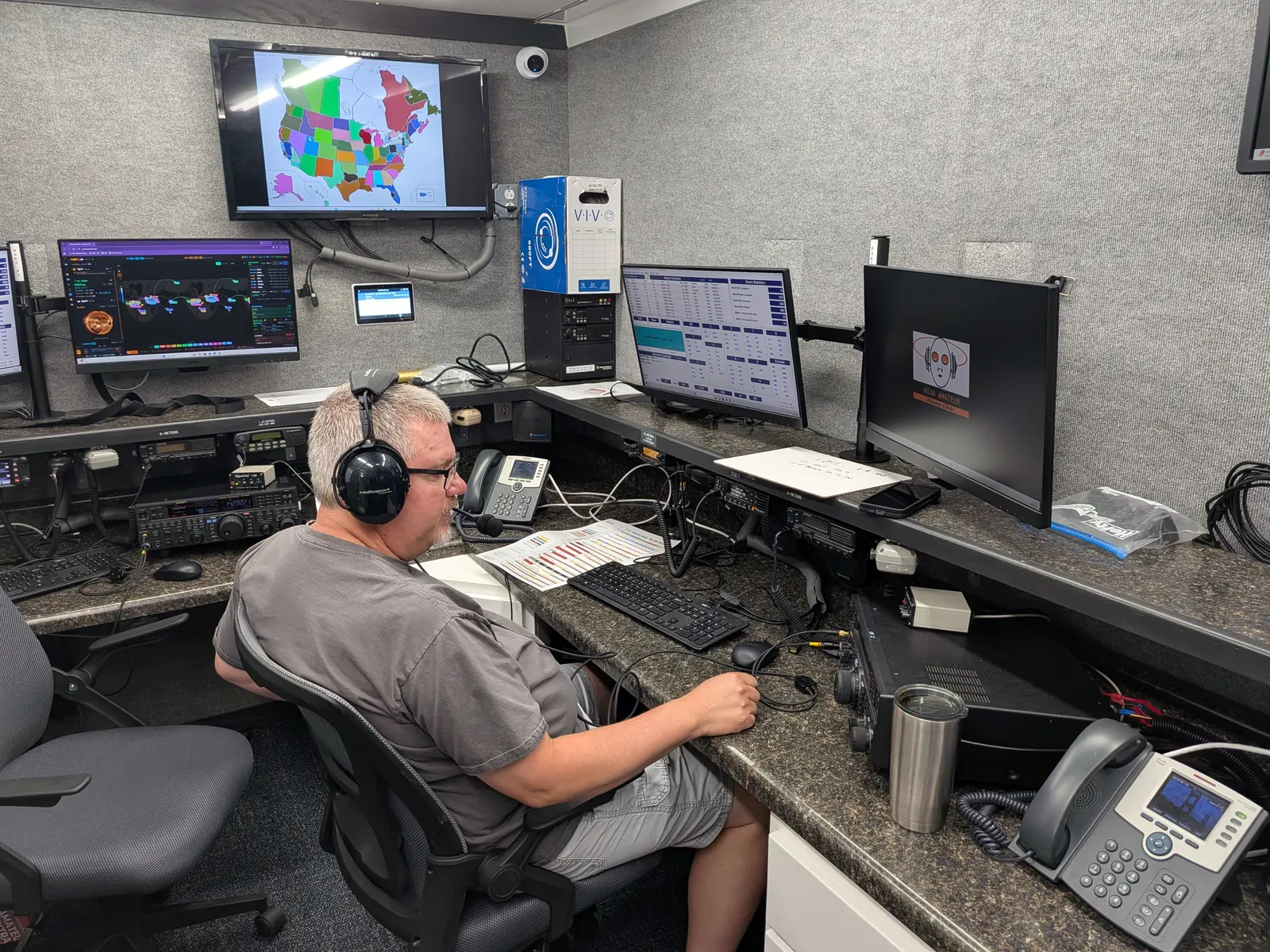 An operator working HF at a radio console inside the communications trailer.